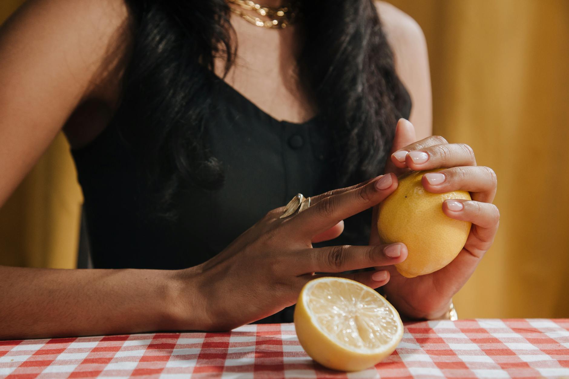 Close-up of a hand holding a lemon-colored vibrator against a minimalistic purple backdrop