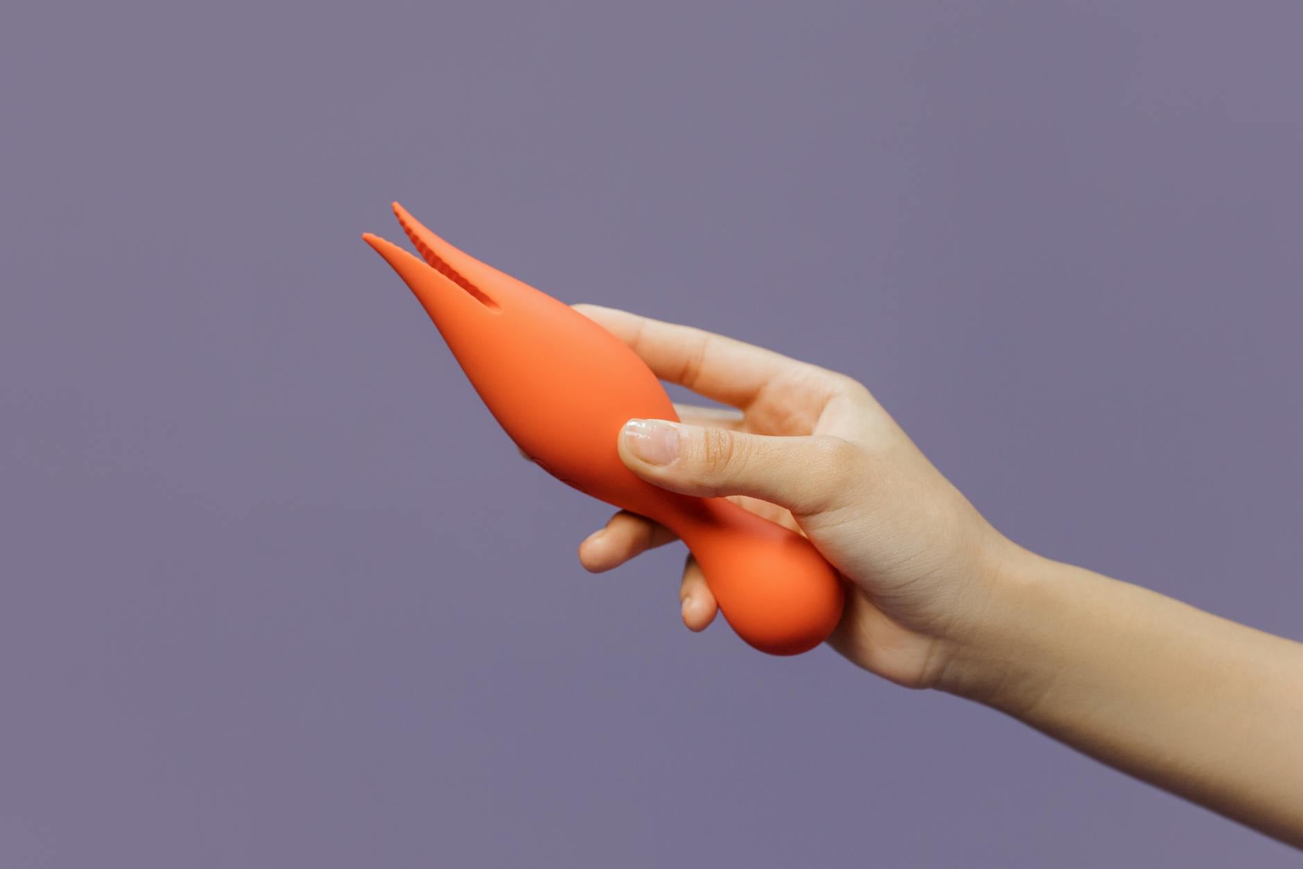 Hand holding a yellow lemon vibrator against a minimalist backdrop, symbolizing postpartum reconnection.