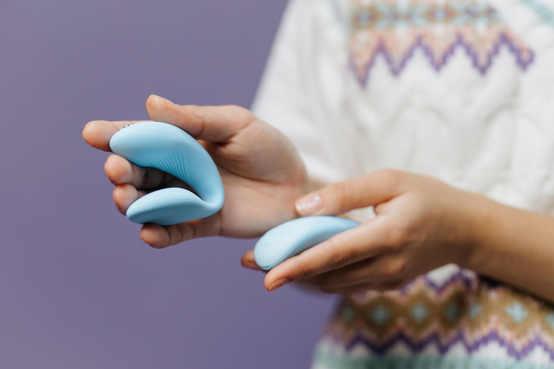 Hands holding a sleek lemon vibrator against a purple background, symbolizing self-discovery and solo pleasure.